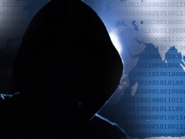 A hacker with their hood up in front of a world map covered in binary code.
