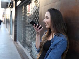 Girl using voice recognition on smart phone outside
